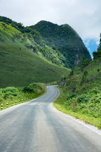 漫长而曲折的农村道路通往老挝的绿色丘陵