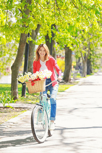 年轻美丽的女孩骑自行车在公园在晴朗的天