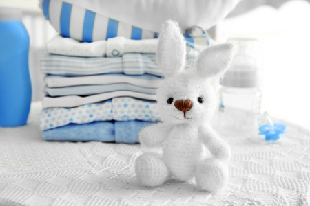针织玩具兔和婴儿衣服在桌子上图片