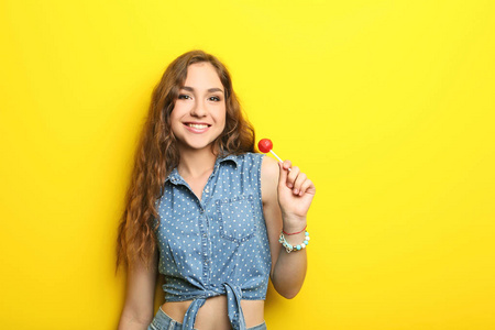 棒棒糖在黄色背景上的年轻女子的画像