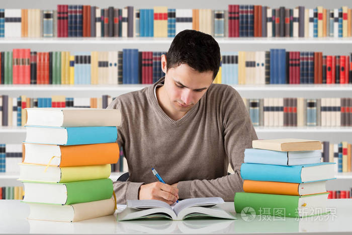 在图书馆书架前学习的年轻男大学生