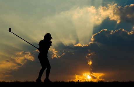 在美丽的日落期间打高尔夫球的剪影高尔夫球手