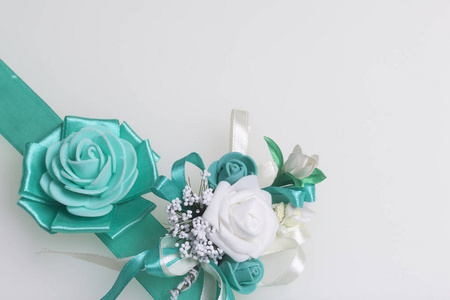 装饰在手中的一朵玫瑰窗体上的翡翠颜色，缝到缎带。附近的婚礼胸花。在白色背景上