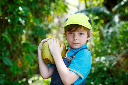 快乐有趣小学龄前孩子男孩手持巨大椰子