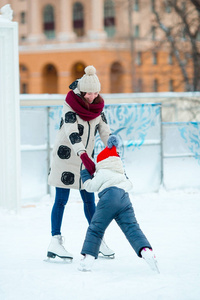 小可爱女孩与母亲和母亲一起在冰溜冰场溜冰