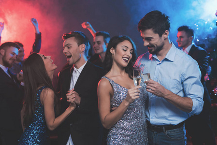 人们在新年晚会上玩得很开心。在前台, 一对情侣在跳舞。他们有香槟的眼镜