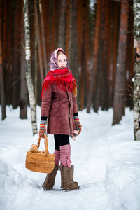 一个带着篮子的女孩走过冬天的森林