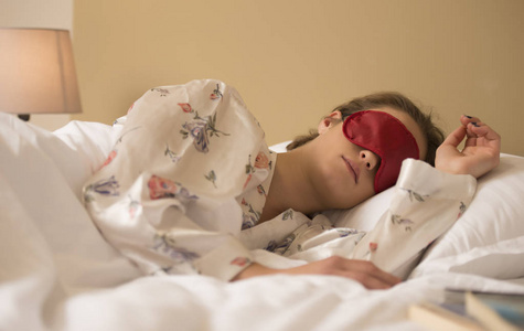 疲惫的女人睡在床上戴着眼罩的睡眠面具