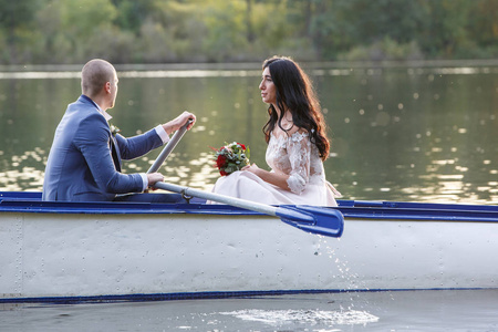 婚礼礼服情侣在日落时, 新娘和新郎的背景下的湖泊。彼此微笑