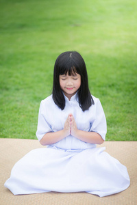 美女的亚洲女孩在公园里祈祷