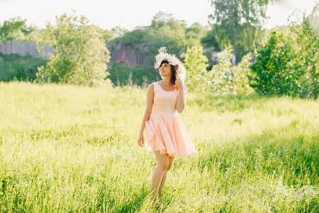美丽的女孩在一个高加索的外观礼服在她的头上的草地上的花圈