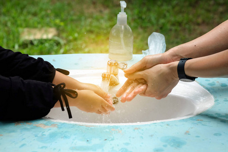 女孩和母亲的手在水槽里洗手