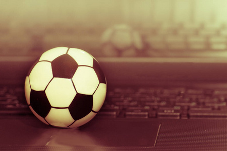 笔记本电脑键盘上的纪念足球。足球比赛的概念