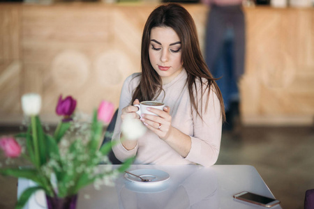 美丽的女孩选址在咖啡馆和喝卡布奇诺