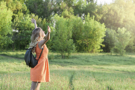 年轻女孩举起手与自由在美丽的自然风景与 copyspace