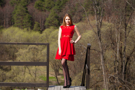 春天公园红色礼服的年轻金发女郎