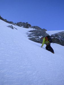 在瑞士的高山山峰上, 雄性登山者在清晨的 couloir 上走向陡峭的雪沟