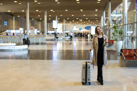 白种女人去机场大厅与手提箱和智能手机聊天