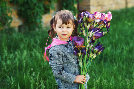 小女孩捧着一束虹膜。婴孩与花