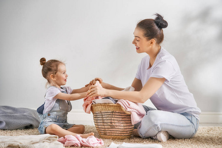 年轻漂亮的女人和孩子女孩小帮手中能开心，并微笑着做在家里洗衣