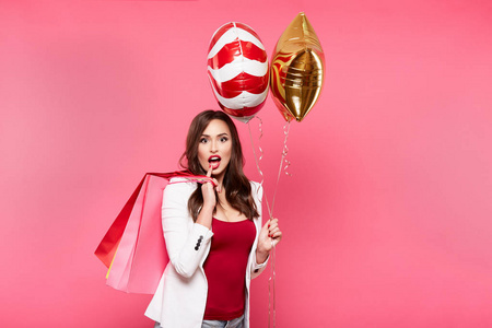 年轻快乐的女人与购物袋和气球摆在粉红色背景, 购物和折扣概念