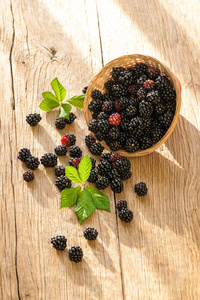 在木制的乡间餐桌上的碗黑莓。天然浆果
