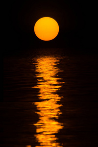 大橙色的太阳反射在黑暗的水上