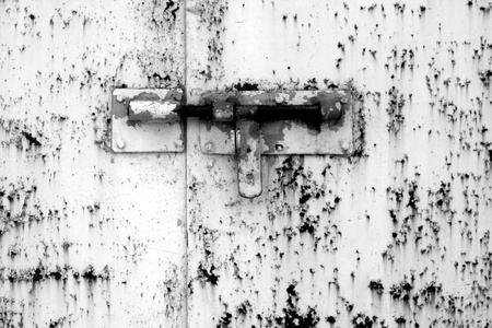 黑色和白色的金属门上的旧挂锁。抽象背景和纹理