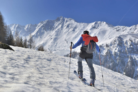 蓝天下的旅游滑雪人攀登雪山