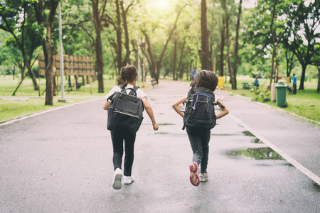 两个小学生跑去上学。两个背着书包的女孩。温暖的秋天的一天。回到学校。小第一年级学生