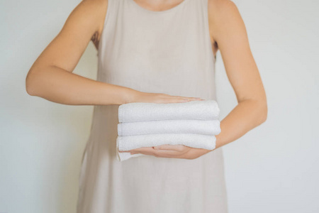 女人拿着一堆白毛巾。酒店服务理念, 洗衣房, 水疗中心