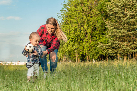 母亲和儿子在草地上玩球。孩子的概念发展。儿童体育概念