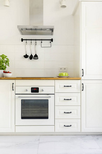 白色橱柜在极小的厨房内部与木台面。真实照片