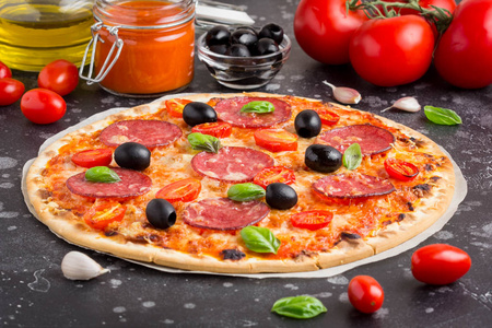 意大利比萨在薄面团与蕃茄酱, 意大利腊肠, 乳酪, 橄榄并且罗勒