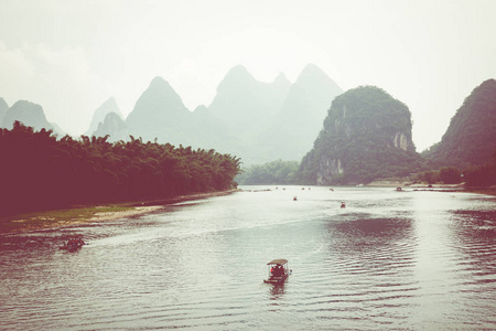 桂林阳朔的绿色森林和喀斯特山脉上的小旅游竹筏的风景景观。阳朔是亚洲最受欢迎的旅游胜地。