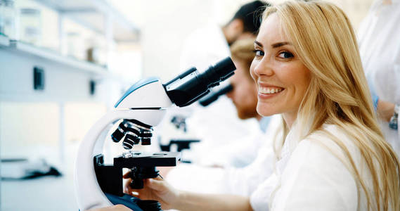 通过在实验室的显微镜的年轻女科学家