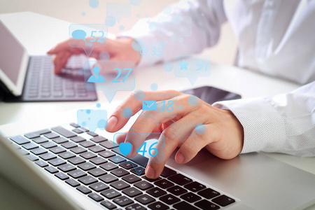 社交媒体和市场营销虚拟图标屏幕的概念. 商人的特写用键盘和笔记本电脑在现代办公室的白色办公桌上键入数字片