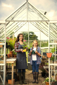 温室中的妇女和孩子在花盆里保存植物