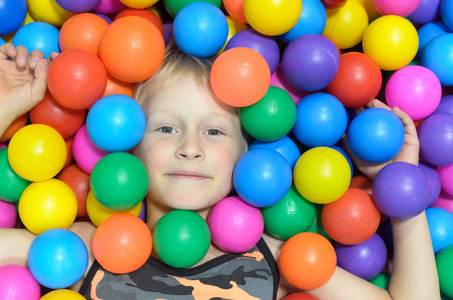 男孩躺在游戏室的五颜六色的球里