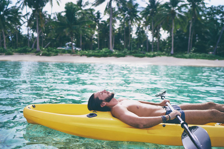 年轻人放松和日光浴在热带平静泻湖的海皮艇