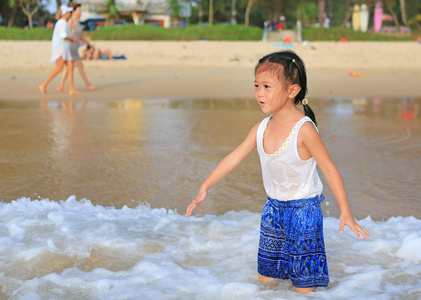 小亚洲女孩在阳光明媚的海滩上玩耍夏日