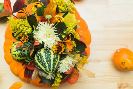 秋季花束的装饰南瓜, 花和叶子在一个花瓶的橙色南瓜在一个木桌上, 股票照片图像