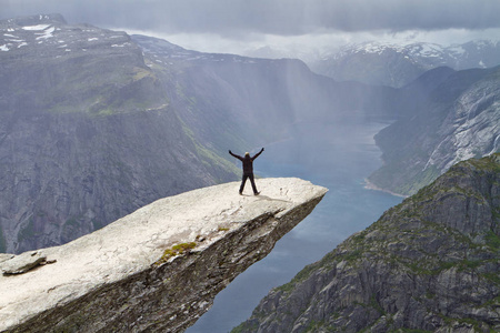 人住在 Trolltunga 岩石 巨人的舌头岩石 和看挪威山风景