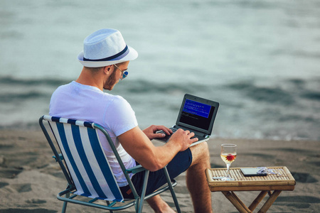 在海滩上使用电脑的人。自由职业者工作