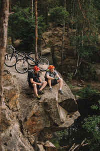 高角度观看快乐的年轻试验骑自行车放松在岩石悬崖骑后
