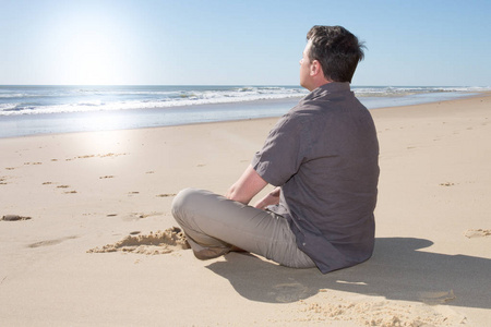 在阳光明媚的日子, 单身男士在海边的沙滩上悠闲地坐着