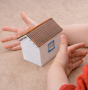 模型的小房子和一只手在光棕色颜色背景