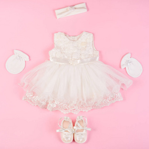 美丽的婴儿礼服与赃物和手套隔离在粉红色的背景