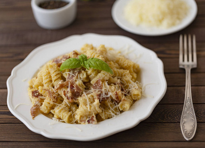 自制面食代表意大利与培根, 鸡蛋, 帕尔马干酪在白色板上的黑暗背景