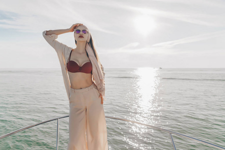 一个穿着夏装的豪华时尚女孩在游艇上享受海上航行, 阳光照射下。